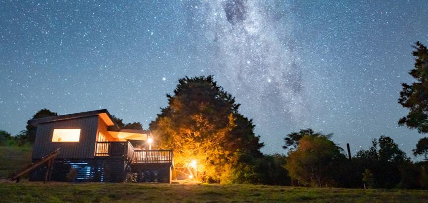 Cabin under a starry night sky with the Milky Way visible